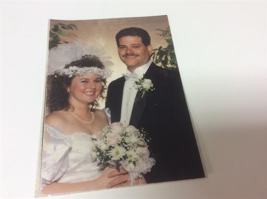 Newlyweds smile brightly while holding a bouquet, captured in a joyful wedding celebration.