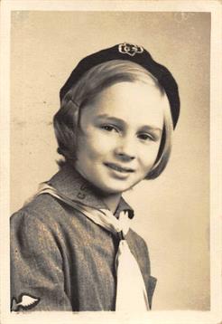 A smiling girl in a beret and scarf displays a relaxed pose in a studio setting.