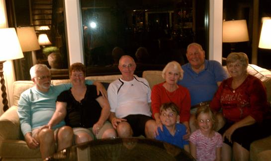 Seven family members gather in a cozy living room, enjoying quality time together at night.