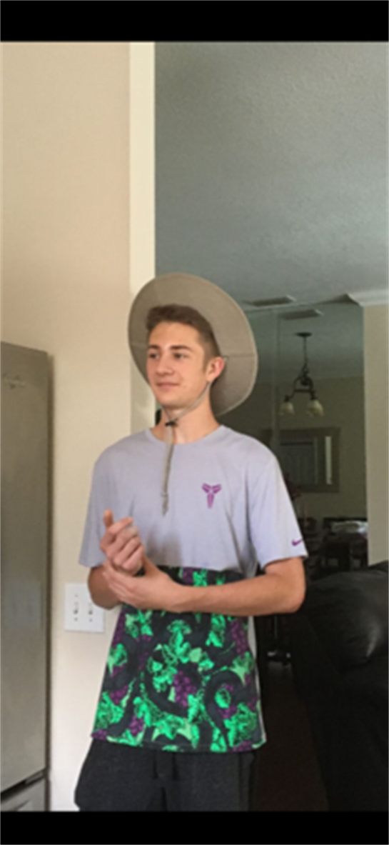 A young man in a sun hat interacts with others in a relaxed indoor setting filled with light.