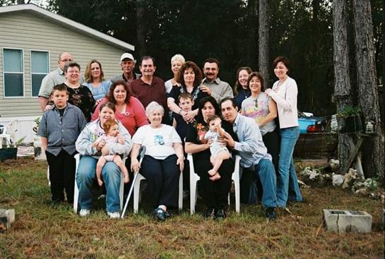 Group of family members enjoying a sunny afternoon together, happily posing in a backyard setting.