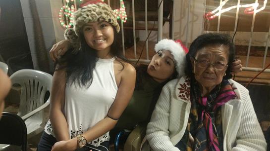 Two friends enjoy quality time with an older woman, smiling and celebrating the festive season.