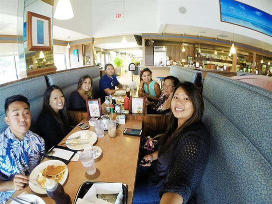 A group of friends gathers around a table, sharing laughs and delicious food at a restaurant.