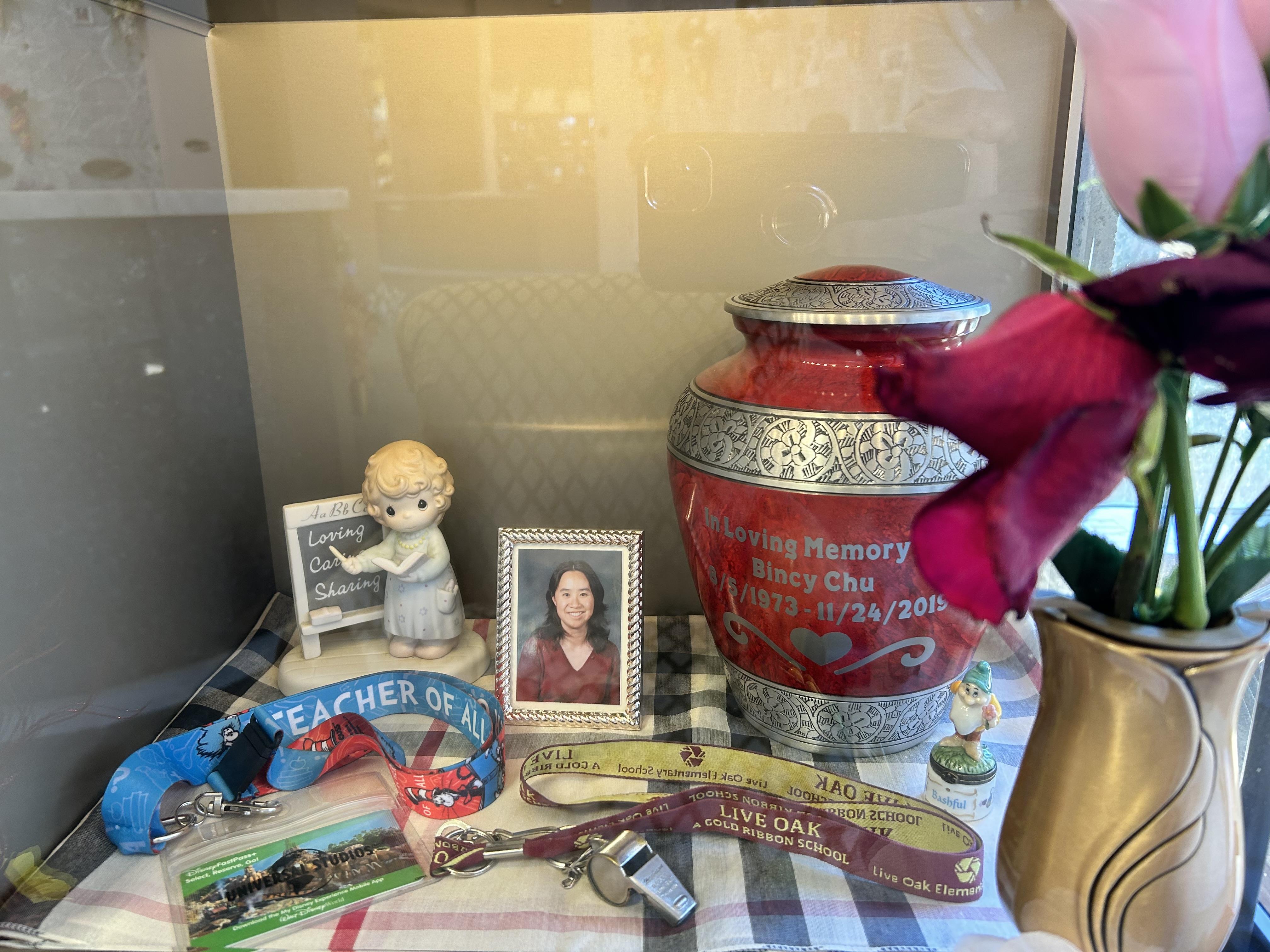 A heartfelt arrangement on a table includes an urn, flowers, and cherished personal items.