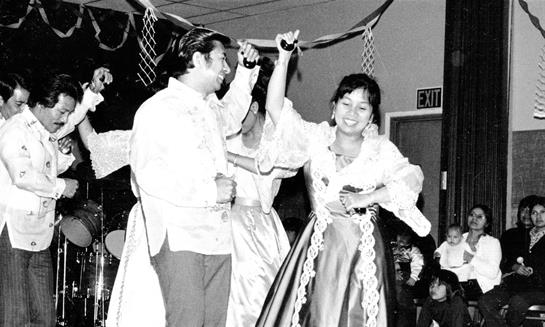 Dancers perform in colorful traditional clothing, celebrating a community event with lively energy.