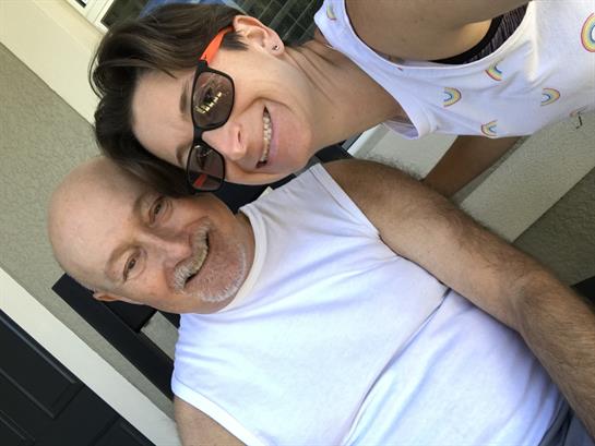 A woman and an elderly man share smiles and laughter on a sunny afternoon while relaxing together.