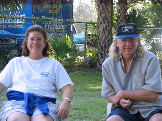 Two people relax in a park during warm weather, enjoying each other's company under palm trees.