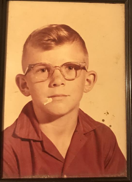 A boy in glasses and a red shirt poses with a cigarette for a vintage look.
