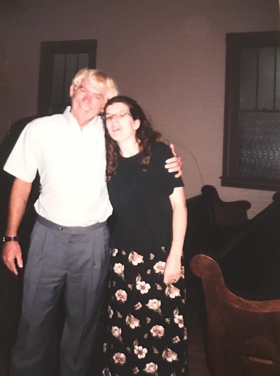 Two individuals embrace while smiling in a warm, inviting environment at dusk.