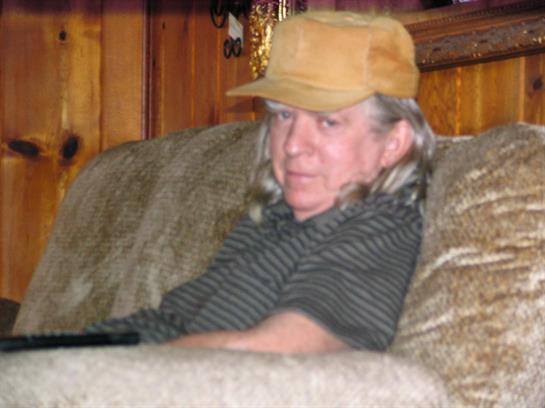 A man relaxes on a couch in a warm and inviting living room, dressed casually.