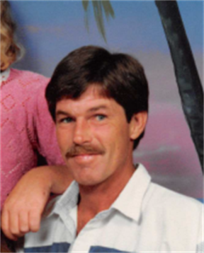 A man with a mustache smiles while seated next to a girl, enjoying a sunny day outdoors.