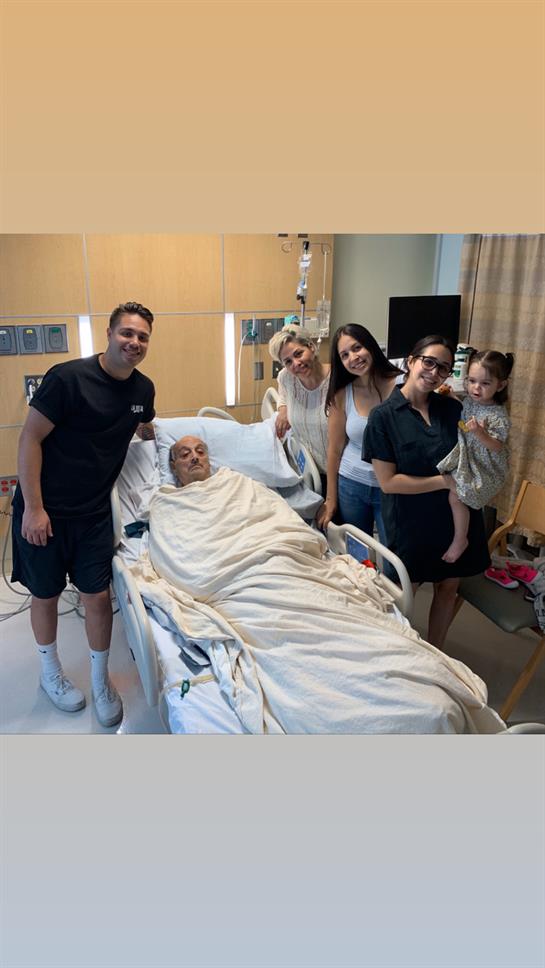 A family visits an elderly man in a hospital bed, sharing smiles and support during his recovery.