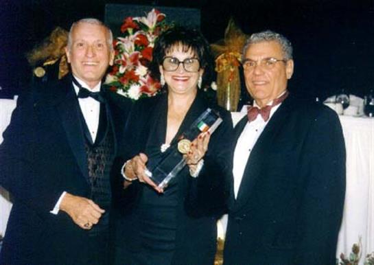 Three individuals pose together at an award ceremony, showcasing a prestigious trophy.