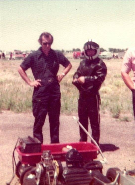 Group of men discuss modifications on a racing cart while preparing for a competition.
