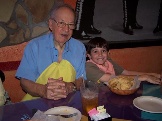 A happy grandfather and his grandson share snacks and fun at a lively restaurant.