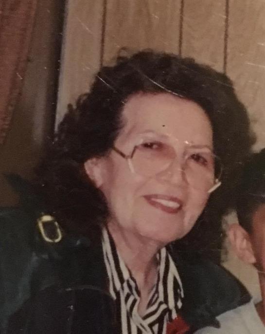 A joyful elderly woman with curly hair enjoys a social gathering at home, surrounded by friends.