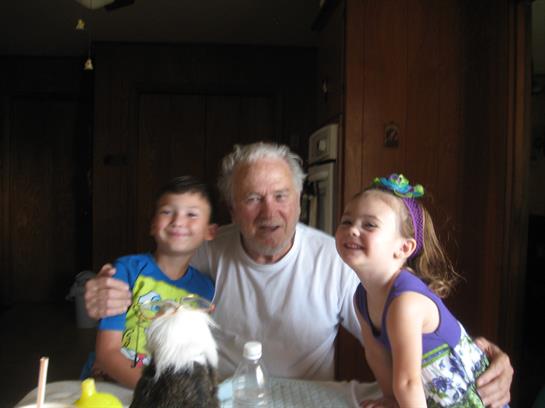Grandfather shares laughter and affection with his two happy grandchildren at home.