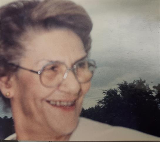 A joyful elderly woman enjoys fresh air, surrounded by nature on a cloudy day.