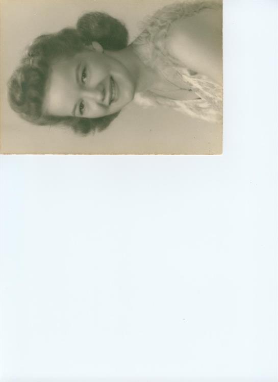 A smiling woman in vintage clothes radiates joy in a cozy setting.