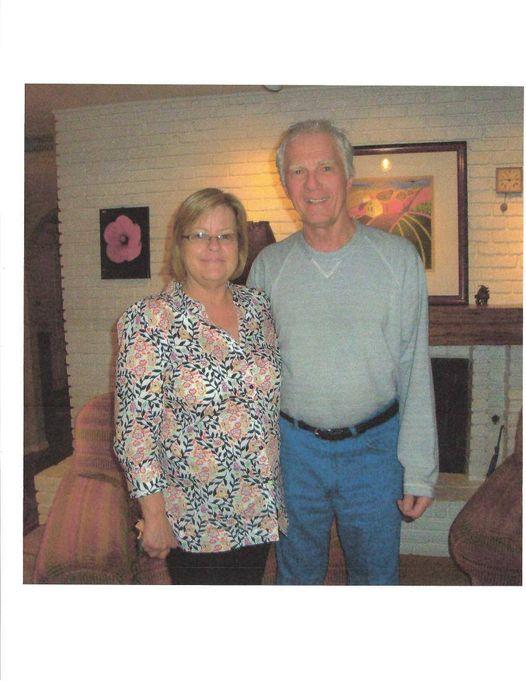 Two people stand side by side in a warm living room, smiling during their visit.