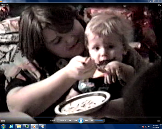 A mother lovingly feeds her young child at a family gathering in a warm and inviting space.