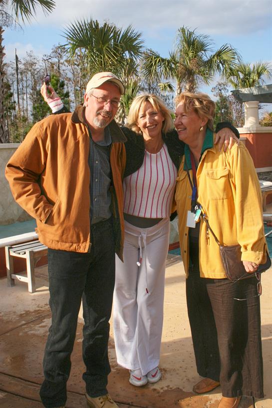 Three friends share laughter and warmth in a sunny outdoor setting, highlighting their joyful bond.