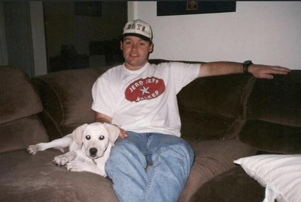A man relaxes on his couch with a friendly dog, enjoying a comfortable moment indoors.