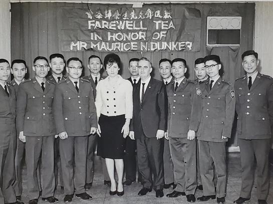 A group of military personnel stands together at a farewell event honoring Mr. Maurice N. Dunker.
