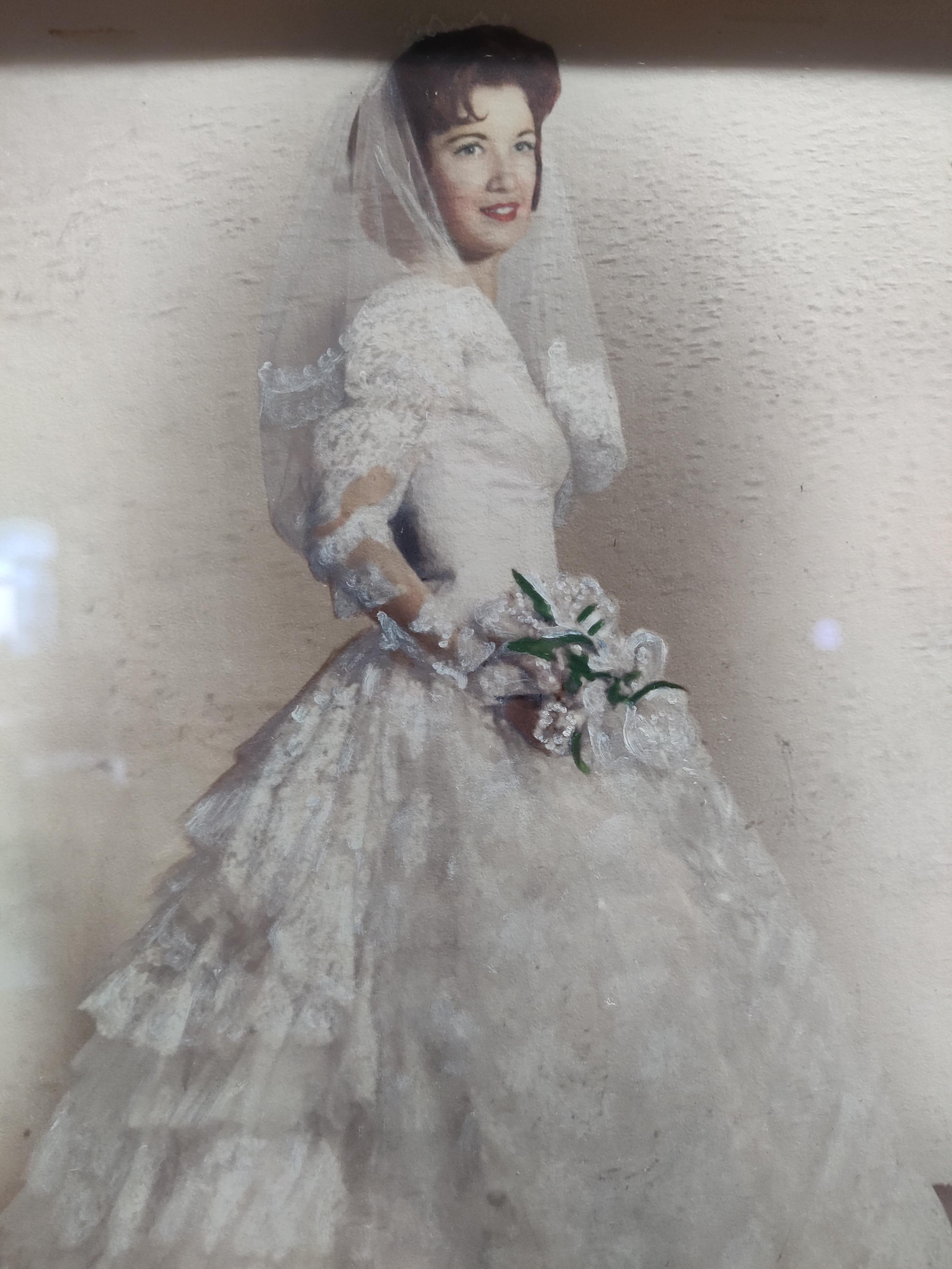A bride in a beautiful vintage white gown holds a bouquet, smiling softly in an ethereal atmosphere.