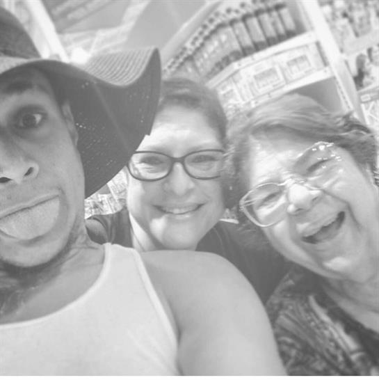 Three people pose together with smiles, enjoying a fun moment in a lively atmosphere.