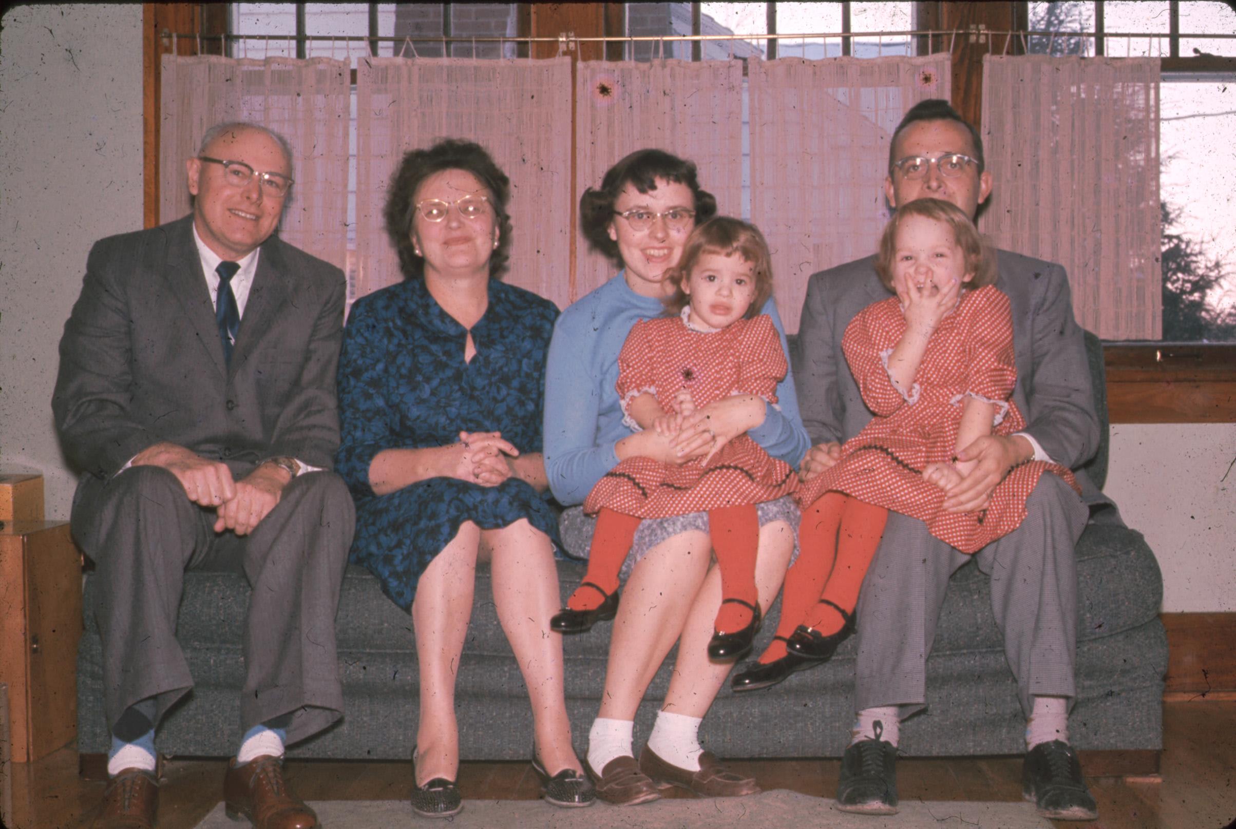 A family sits together on a couch, enjoying a warm afternoon in a comfortable living room.