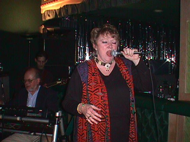 A captivating singer performs with a keyboardist in a lively setting.