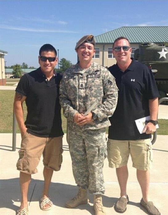 Groups of military personnel and friends celebrate together in a cheerful outdoor setting.