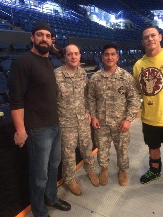Three military personnel stand alongside a well-known celebrity at a sports arena.