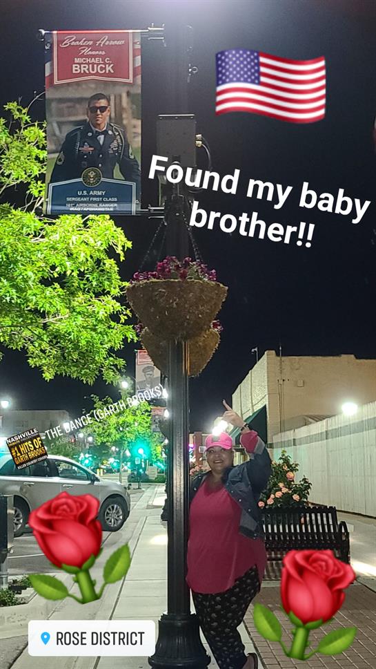 Joyful woman expresses excitement about finding her brother near a memorial under streetlights.
