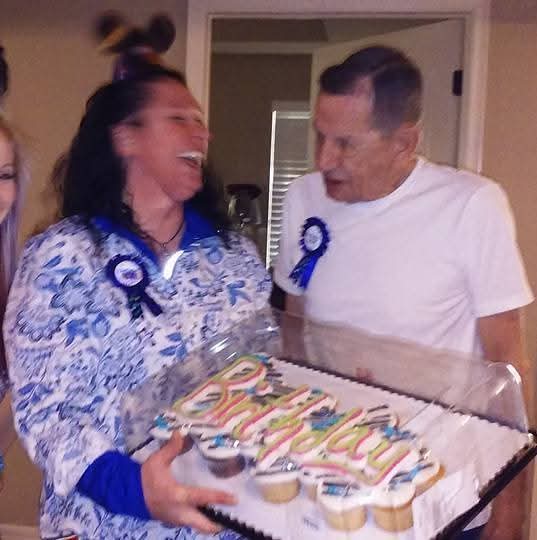 A man and woman holding a tray of cupcakes