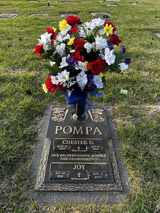 A vibrant arrangement of flowers adorns the grave of Chester G. Pompa, honoring his memory.