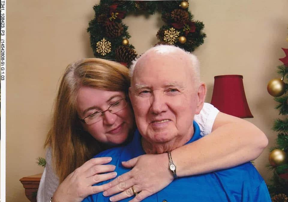 A woman gently embraces an older man, conveying love and joy during a festive gathering.