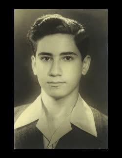 A young man displays a charming expression while looking directly at the camera in a studio.