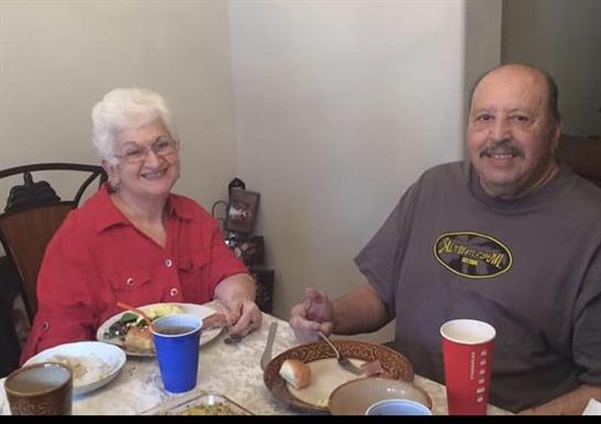 Two smiling individuals enjoy their meal together at a dining table filled with food and drinks.