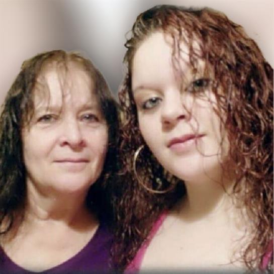 Two women with curly hair pose closely, highlighting their expressions and shared joy.