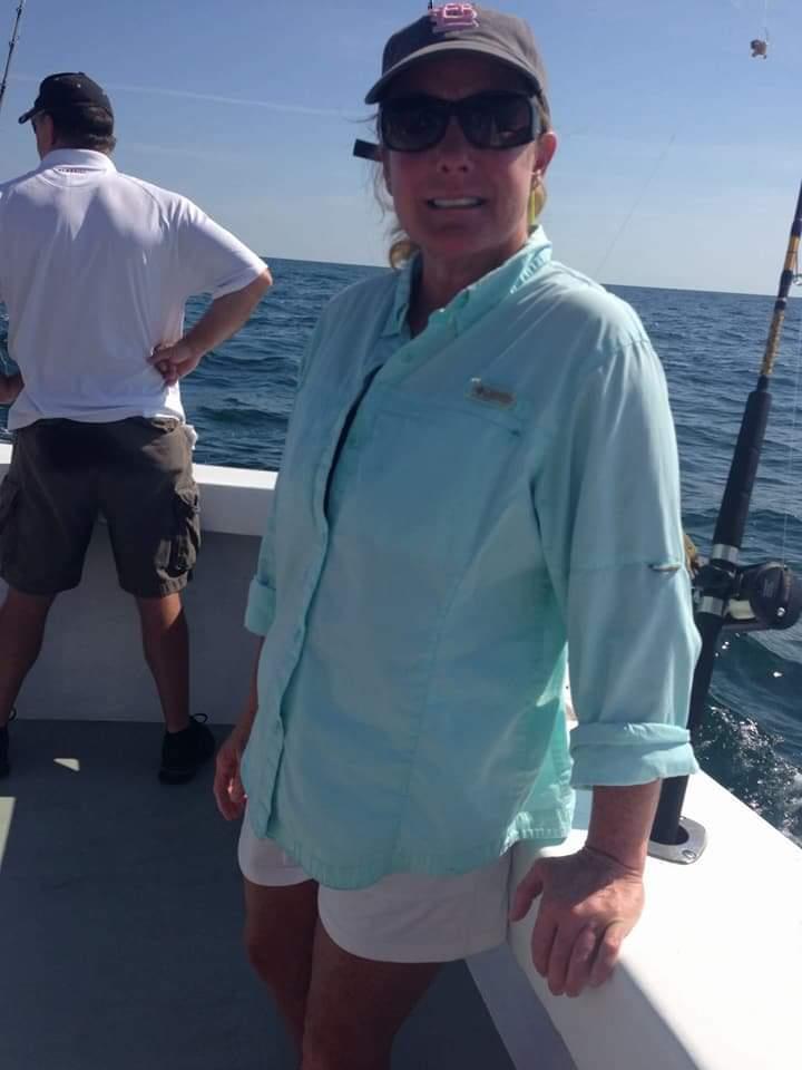 A group is fishing on a boat in clear blue waters under a sunny sky, enjoying their time.