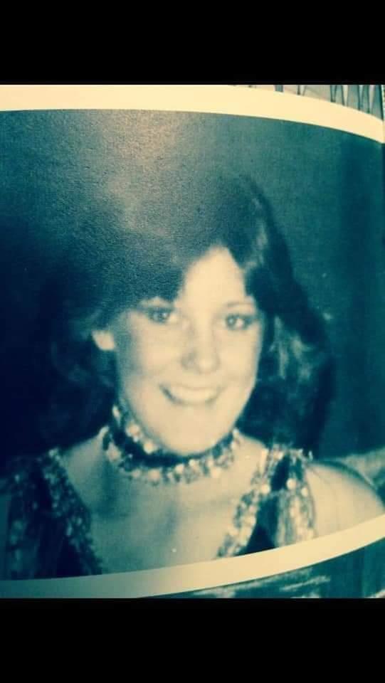 A joyful girl in formal attire with wavy hair and a charming smile.