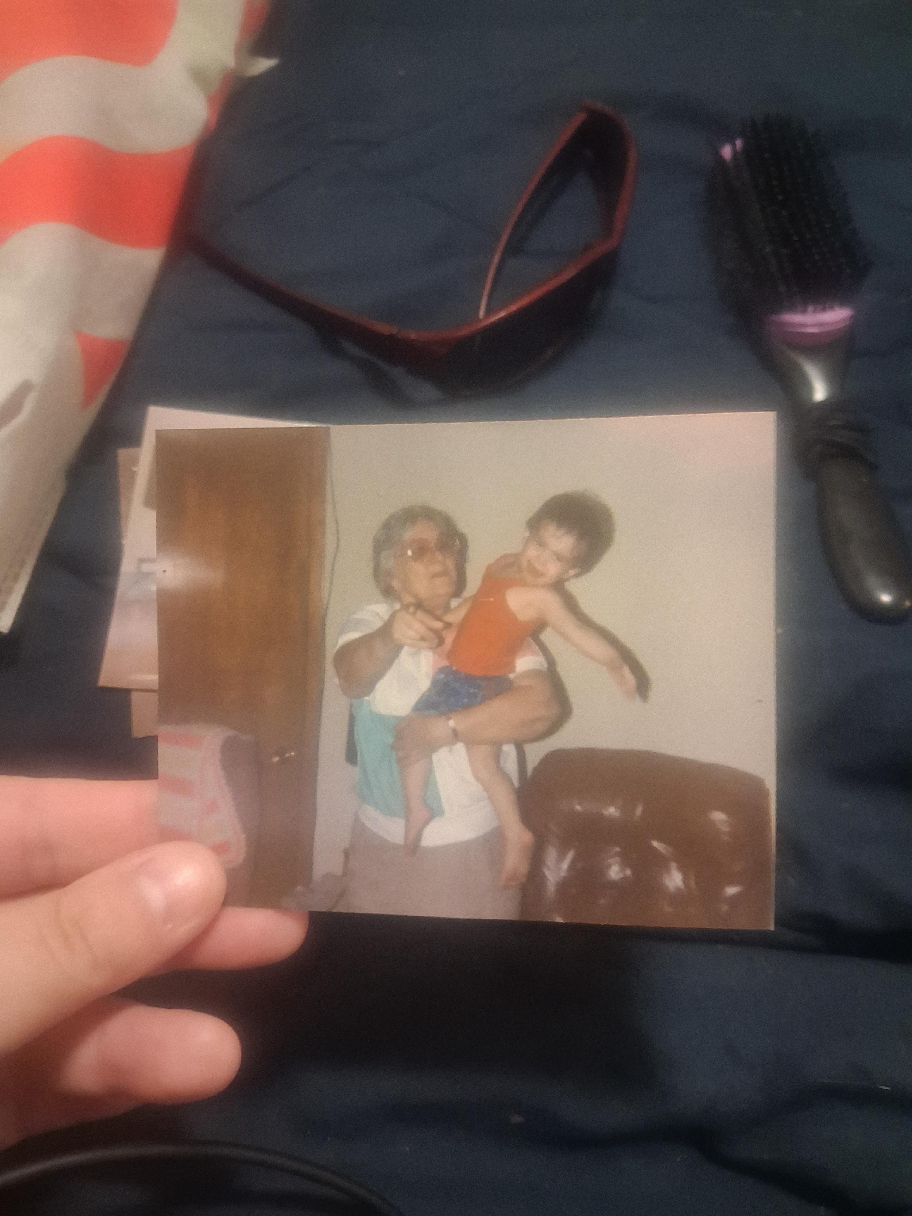 A grandparent joyfully holds a child, both smiling in a warm living room atmosphere.