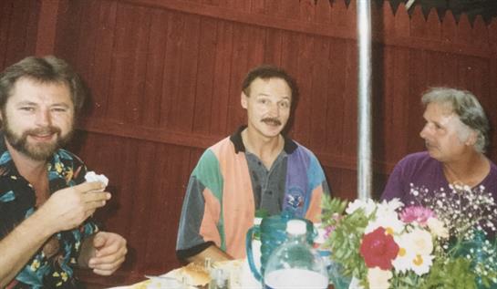 Two individuals converse and share food at a relaxed gathering, showcasing a friendly atmosphere.