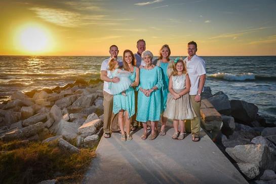 A family enjoys sunset on the shoreline, appreciating the scenery and each other's company.