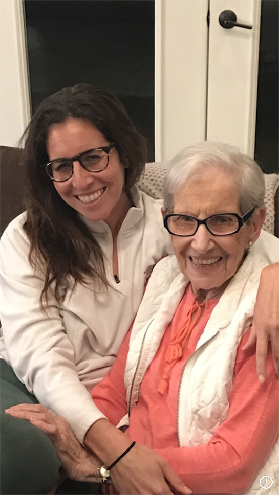 Granddaughter and grandmother share a joyful moment together while sitting on a couch at home.