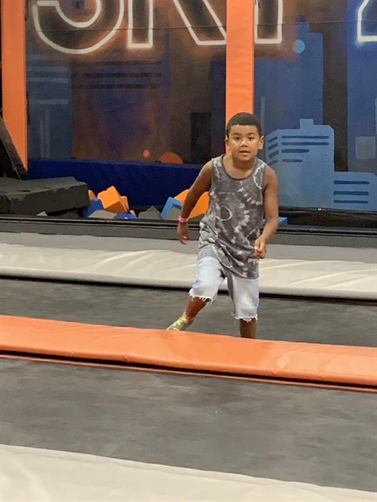 A child runs excitedly on a trampoline, enjoying playful moments in a lively trampoline park.