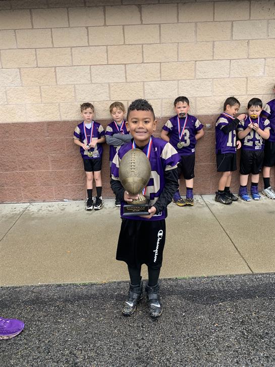 Young football player proudly displays his trophy after a victorious championship match.