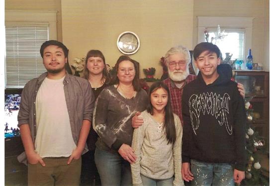 Seven family members gather together in a warm living room, smiling and embracing festive spirit.